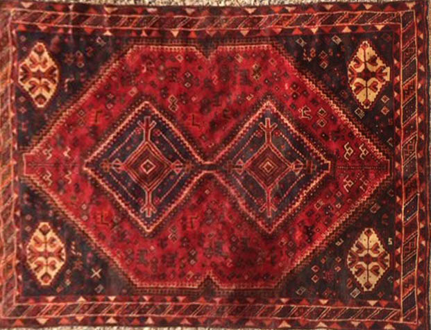 A MIDDLE EASTERN DESIGN WOOLLEN RUG Having two hooked lozenge medallions, zoomorphic patterns and
