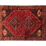 A MIDDLE EASTERN DESIGN WOOLLEN RUG Having two hooked lozenge medallions, zoomorphic patterns and