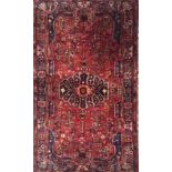 A HAMADAM WOOLLEN RUG The central medallion on a red field, flanked by floral designs and a