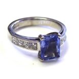 A PLATINUM, SAPPHIRE AND DIAMOND RING The baguette cut sapphire in a raised mount with Princess