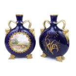 A PAIR OF 19TH CENTURY ENGLISH PORCELAIN MOON FLASKS Having snake and mask handles on blue ground