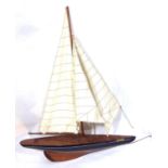 A 20TH CENTURY MAHOGANY MODEL OF A SAILBOAT With white canvas sail and movable rudder, inscribed