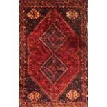 A BOKHARA WOOLLEN RUG Having two rows of five geometric form guls on a dark red field, contained