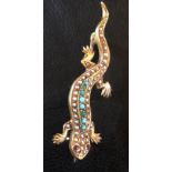 A 9CT GOLD BROOCH FORMED AS AS LIZARD With ruby eyes and a pearl and turquoise inset back. (4.7cm)
