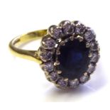 AN 18CT GOLD, SAPPHIRE AND DIAMOND CLUSTER RING The single oval cut sapphire edged with diamonds (