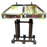 A TIFFANY STYLE ART DECO DESIGN TABLE LAMP With coloured panelled glass shade over rustic metal