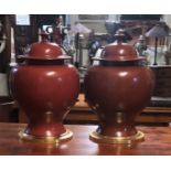 TWO LARGE CERAMIC BALUSTER VASES AND COVERS In red oxide, on giltwood stands. (53cm)