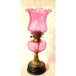 A VICTORIAN CRANBERRY GLASS AND BRASS OIL LAMP On circular black glass base. (58cm)