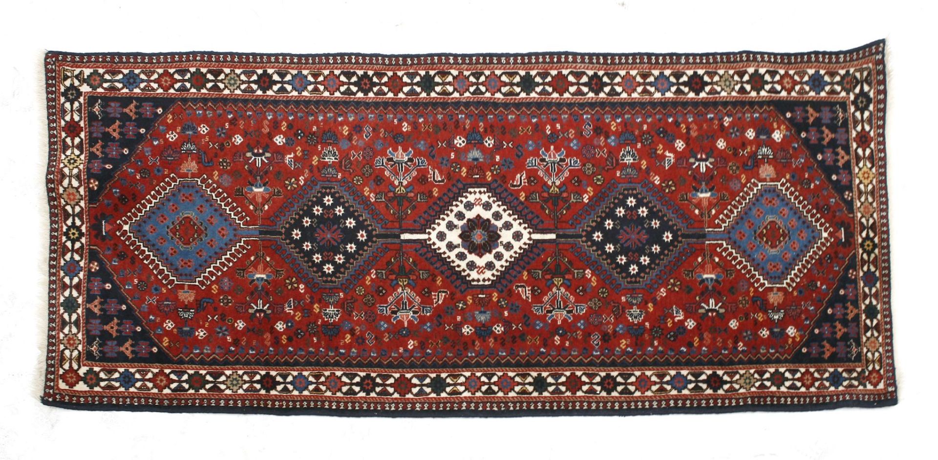 A Yalemah runner, with five geometric medallions, within a red floral field,200 x 87cm