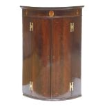 A George III strung and inlaid mahogany bow-fronted hanging corner cupboard,with brass 'H' shaped