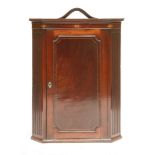 A George III strung mahogany hanging corner cabinet,the top with a later mount over an inlaid frieze