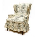 A George III-style wing armchair,now with a loose cover, on carved mahogany front legs