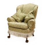 A wing armchair,mid 20th century, with loose covers, on carved claw and ball front legs