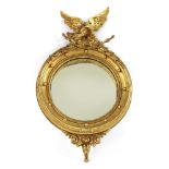 A George III giltwood convex wall mirror,with a spread-eagle over a ball-mounted convex frame and