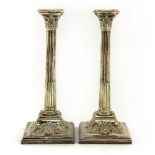 A pair of silver-plated Corinthian column candlesticks,terminating in sloping square bases,