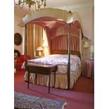 A reproduction four-poster bed,the slender turned uprights with grained decoration and a pink fabric