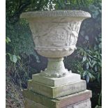 A pair of composition stone urns,the sides moulded with trailing vines, on pedestal bases,62cm