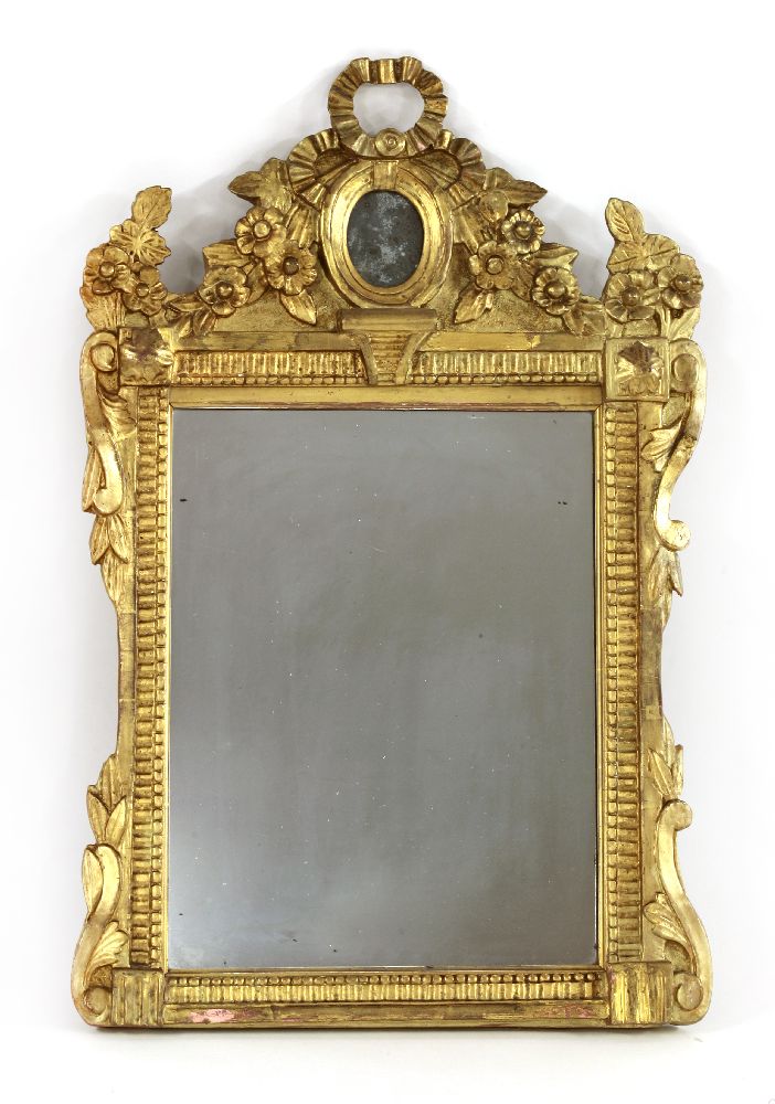 A carved giltwood wall mirror,late 19th/early 20th century, the shaped crest with ribbon-tied