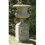 A composition stone urn and pedestal,with a part reeded body, the square plinth moulded with a