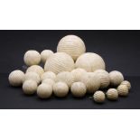 A large collection of various turned ivorine balls, each with spiral reeded decoration,