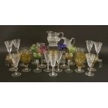 A collection of glassware including, nine cut-glass champagne flutes, eight goblets with coloured