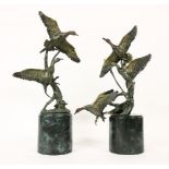 A pair of contemporary figures of ducks in flight, each with gilt highlight and on turned marble