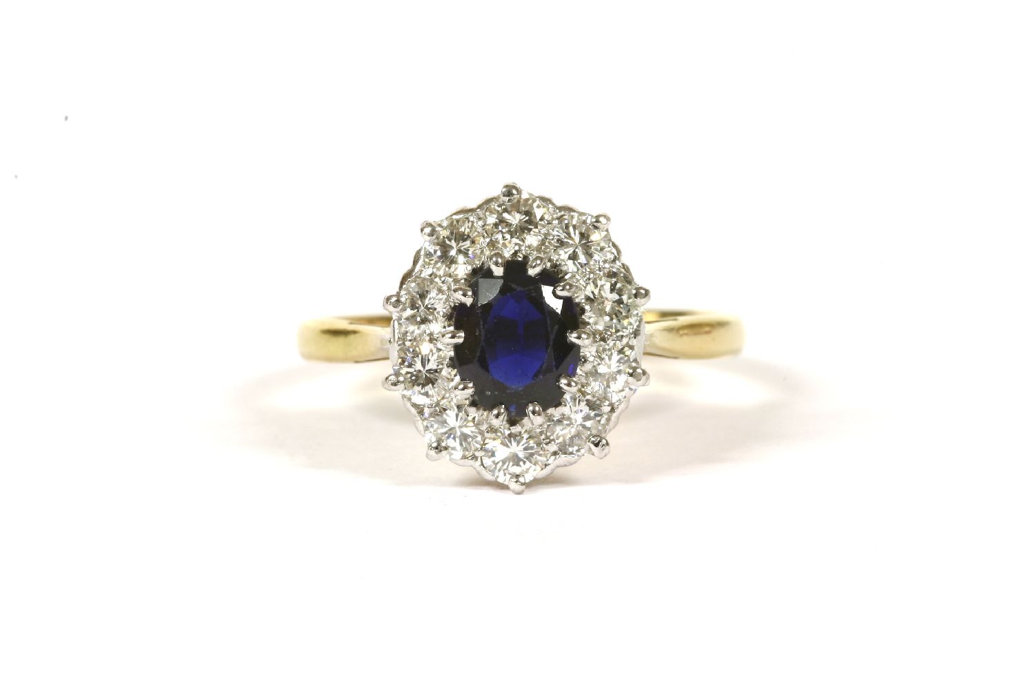 A sapphire and diamond oval cluster ring, with an oval mixed cut sapphire, claw set to the centre, a