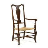 An 18th century fruitwood countrymade elbow chair, with rush seat on stretchered turned supports,