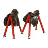 A PAIR OF HORSE'S SADDLES,each on a red leather covered stand with horseshoe feet,89cm high (2)