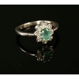 A 9ct white gold emerald and illusion set diamond daisy cluster ring, to a plain polished shank,