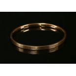 A 9ct gold hollow flat section slave bangle, 6.54g, with textured decoration to exterior