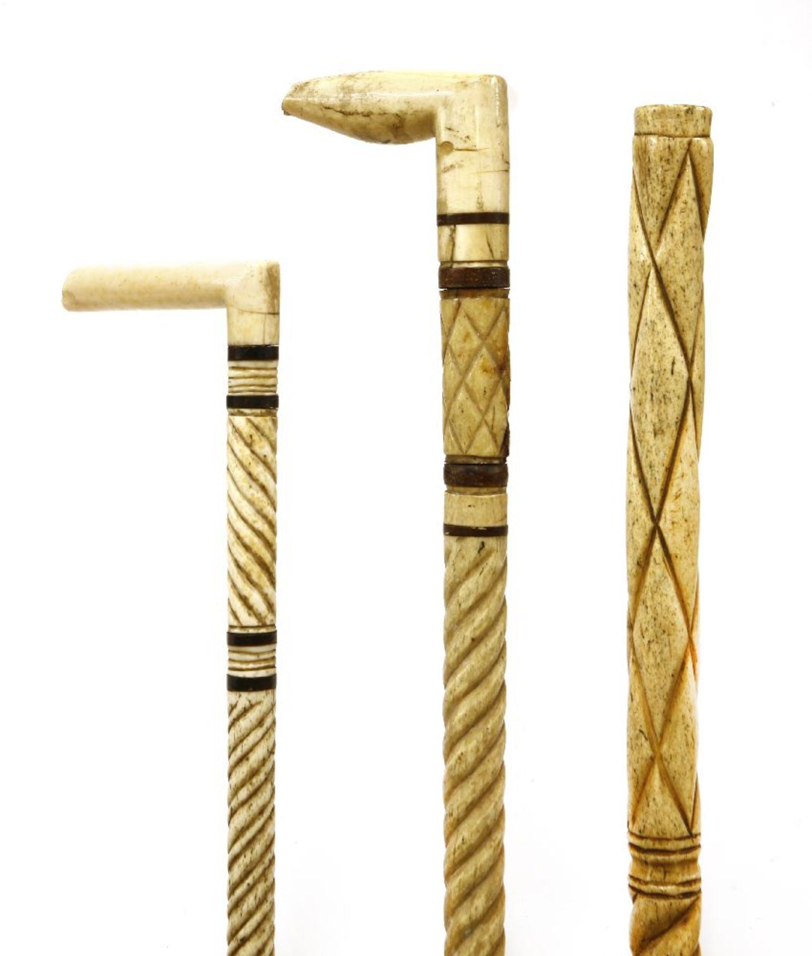 Three marine ivory and whalebone walking sticks,the first with carved angled handle, four baleen