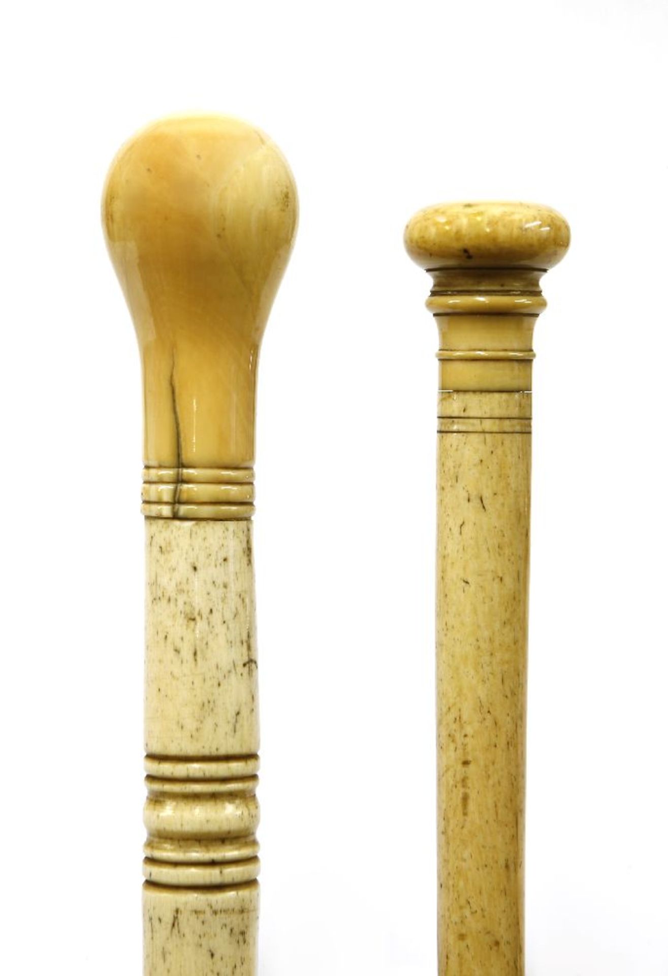 Two marine ivory walking sticks,the first with a flattened disc and line turned handle, over a