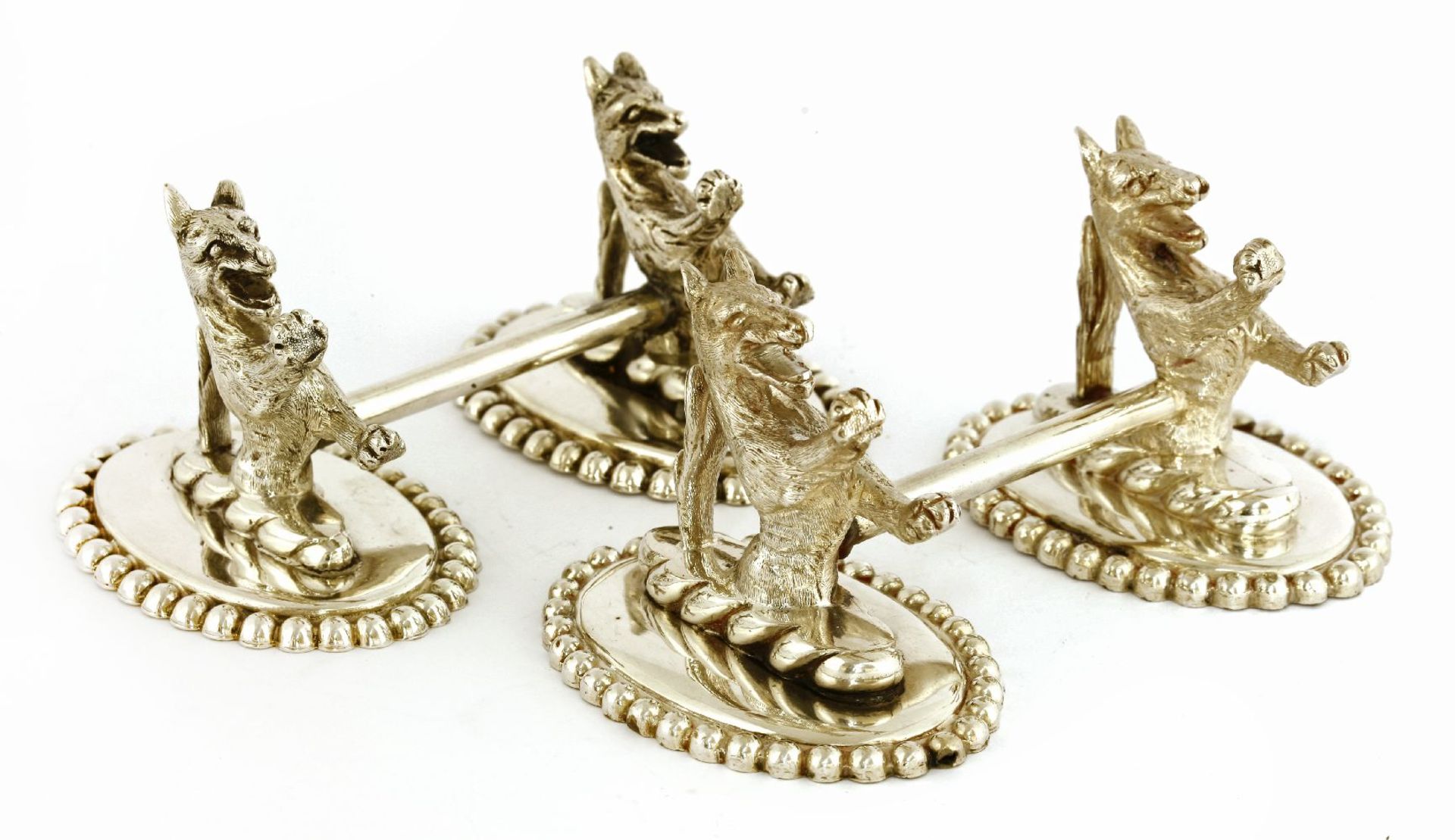 A near pair of electroplated knife rests,in the form of armorial wolves on oval beaded bases,14cm