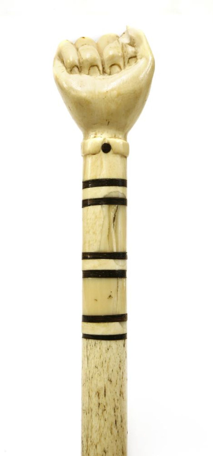 A marine ivory and whalebone walking stick,with a clenched hand over six baleen discs, on a plain