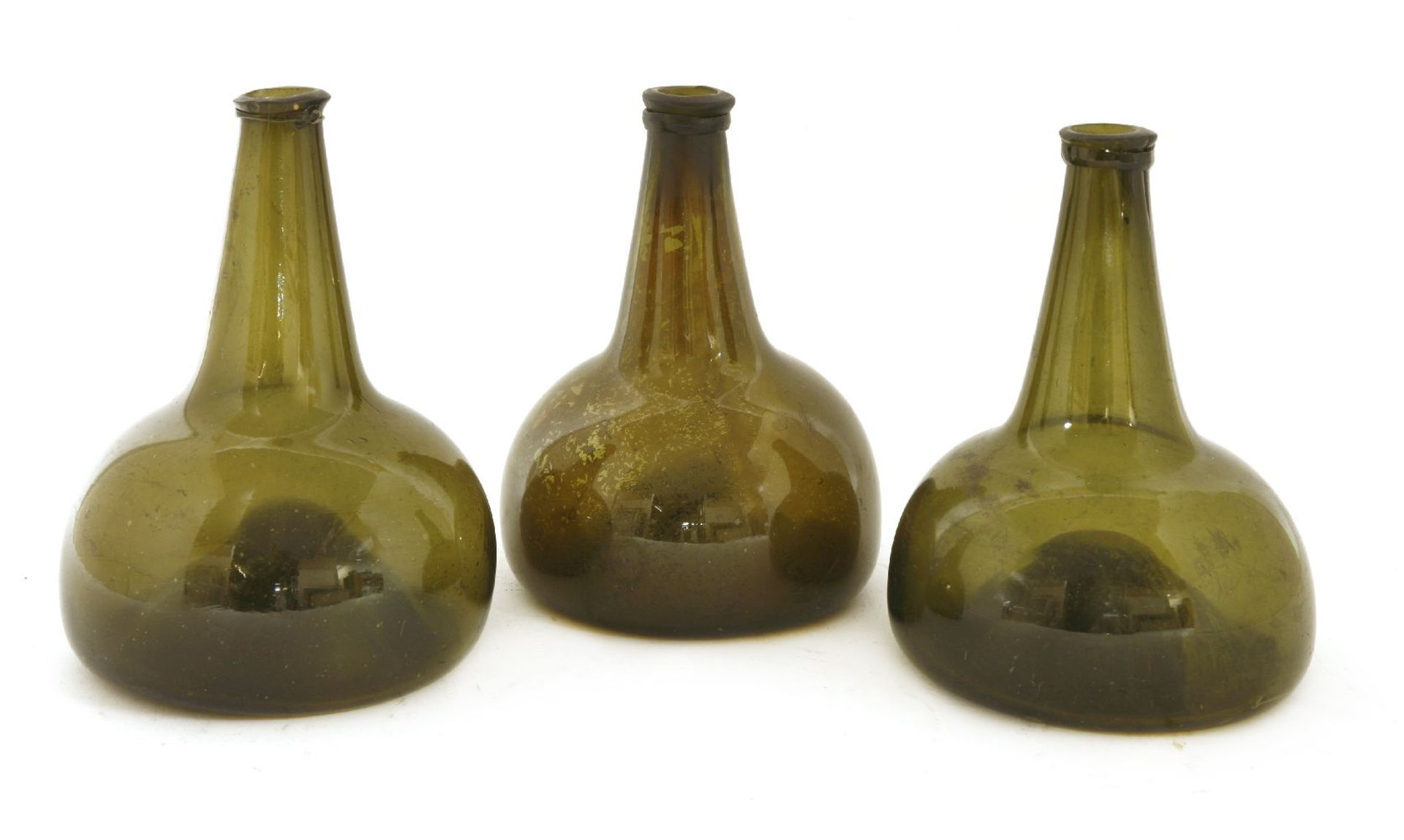 Three green glass globe and shaft wine bottles,probably 17th century, each with a snapped pontil,