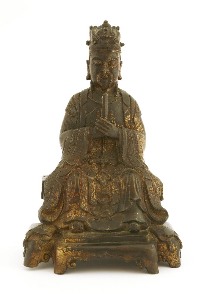 A Chinese bronze figure, Ming dynasty or later, seated on a raised platform with both hands held