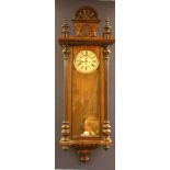 A walnut and ebonised Vienna regulator, the glazed panel door enclosing circular enamel dial and