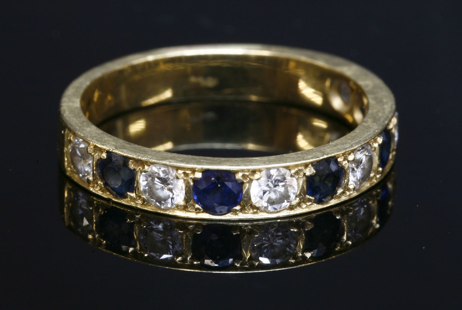 A gold sapphire and diamond half eternity ring, with alternating brilliant cut diamonds and circular