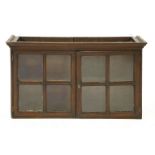 An oak wall mounted cabinet, 18th century, the moulded cornice over two astragal glazed doors,