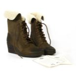 A pair of Ugg boots, brown sheepskin with a white sheepskin fur interior with lace up front and