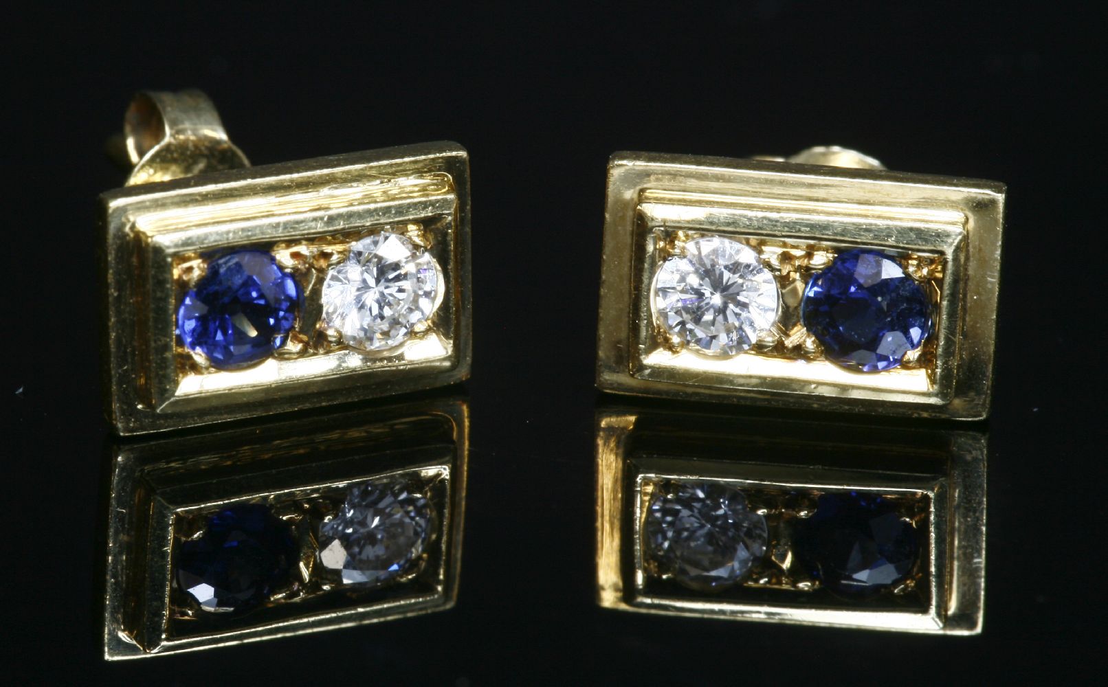 A pair of gold two stone sapphire and diamond stud earrings, with a brilliant cut diamond and a