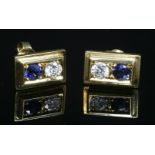 A pair of gold two stone sapphire and diamond stud earrings, with a brilliant cut diamond and a