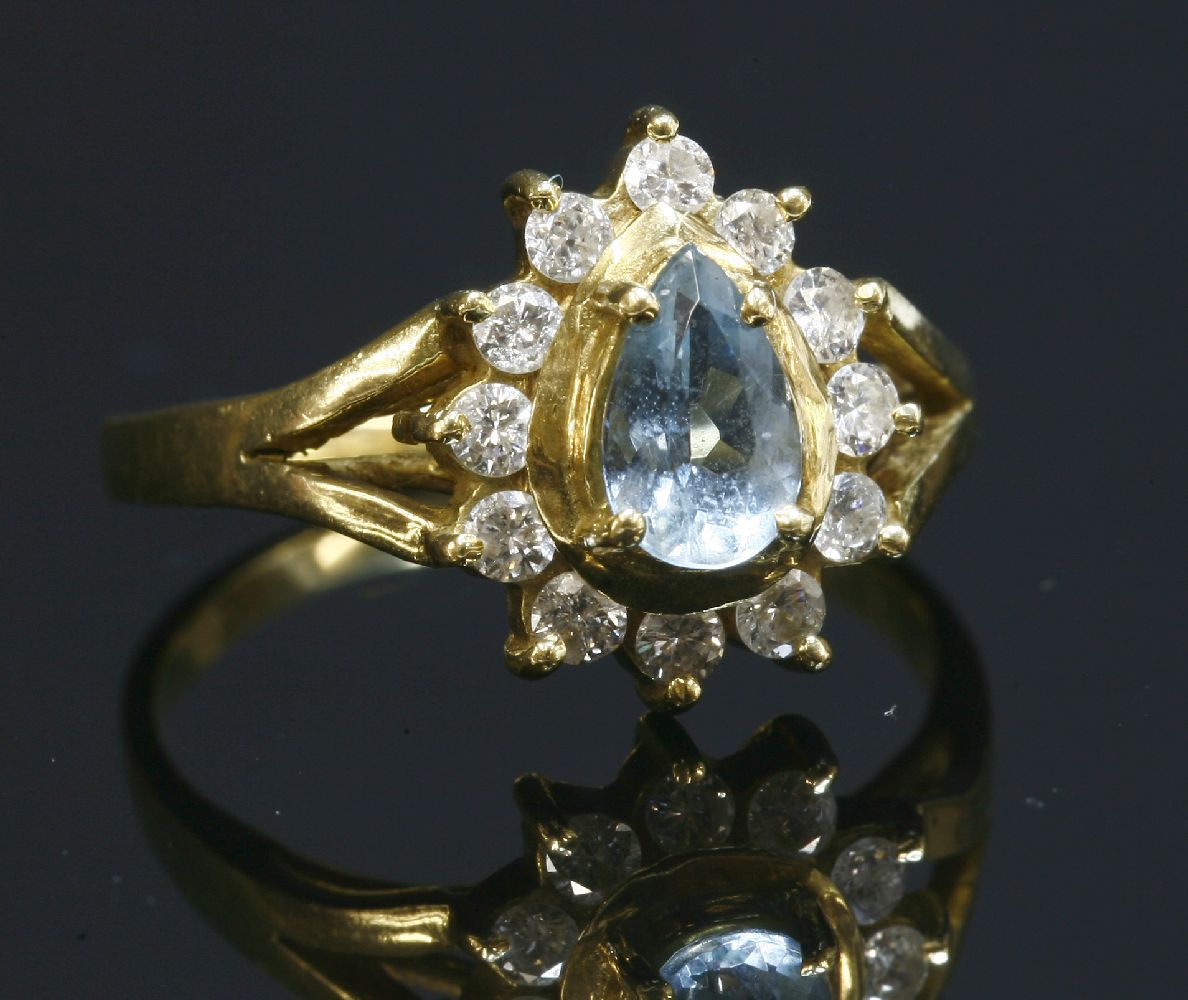 An aquamarine and diamond gold cluster ring, with a pear cut aquamarine, four claw set to the