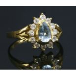 An aquamarine and diamond gold cluster ring, with a pear cut aquamarine, four claw set to the