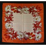 A Caroline Herrera orange silk scarf, with a printed floral design with a spotted centre, together