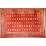 A Persian Bokhara carpet, the brick red fields with repeating elephant's foot motifs within a