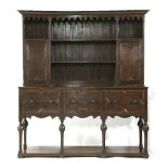 An early 20th century Jacobean style oak dresser and delft rack, the fret cut frieze over shelves