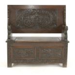 An oak monks bench, the carved hinged top above hinged storage section on block feet, 107cm wide,
