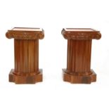 A pair of low modern column pedestals with cupboards